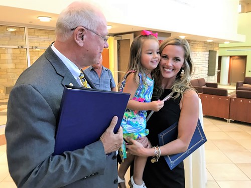 Breana Dieringer and her daughter speak with Dr. Robert Wanker at a scholarship ceremony.