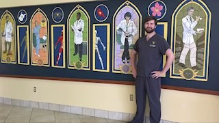 Ian Weaver poses inside a mural he created in the Health Sciences Center.