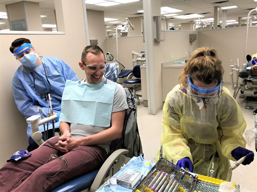 Jay Solensky, left, and Taylor Sherry, right, treat a patient during Veterans Oral Health Day