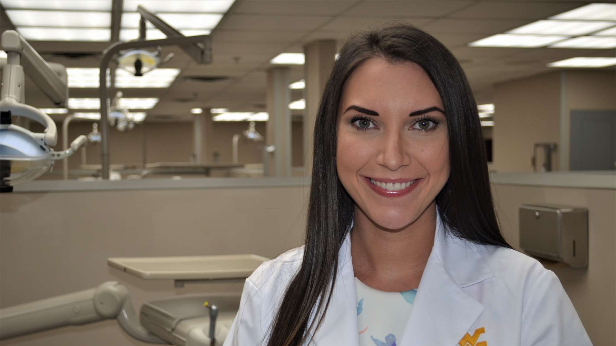 Corina Torres poses in her white coat in the School of Dentistry main student clinic. 