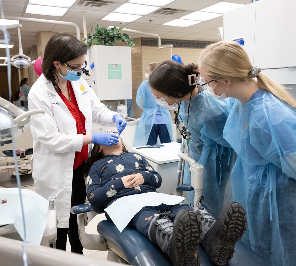 Faculty and students work with a child in the pediatric dentistry clinic. 